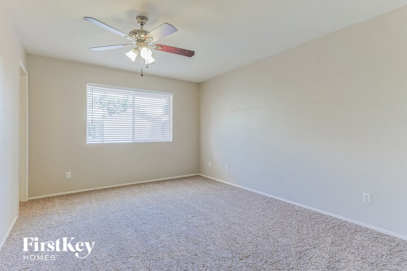 an empty room with a ceiling fan and a window