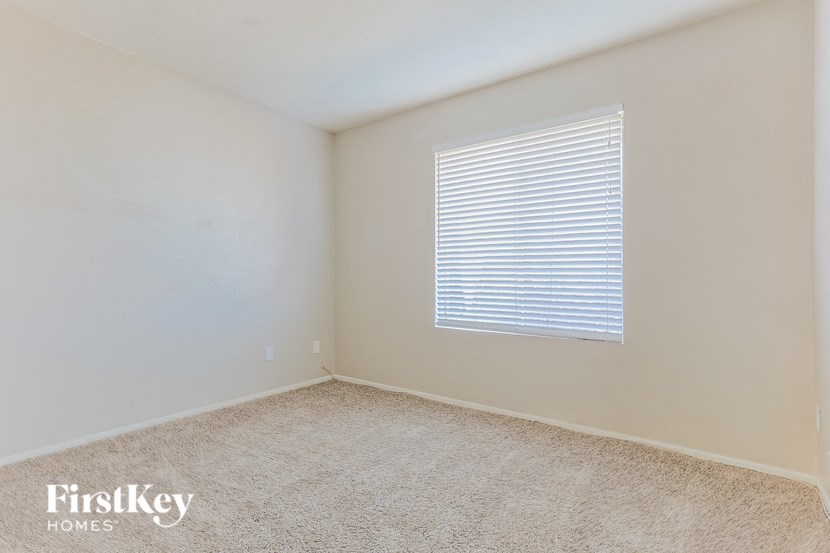 a bedroom with a window and a carpeted floor