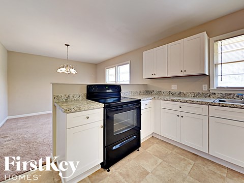 A kitchen with a black oven and white cabinets.