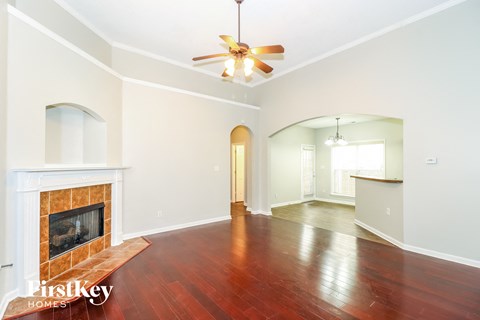 A spacious room with a fireplace and a ceiling fan.