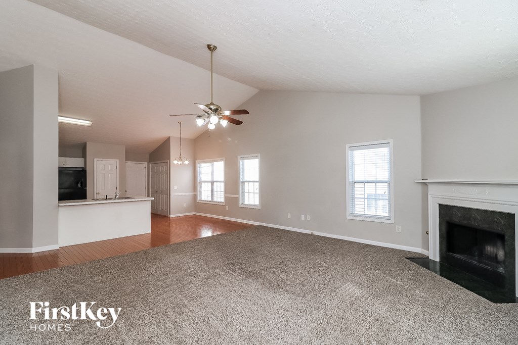 an empty living room with a fireplace and a ceiling fan