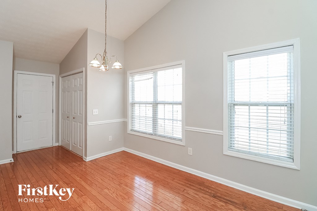 a living room with wood flooring and two windows and a door