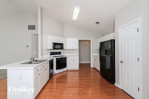 a kitchen with white cabinets and black appliances and a wood floor