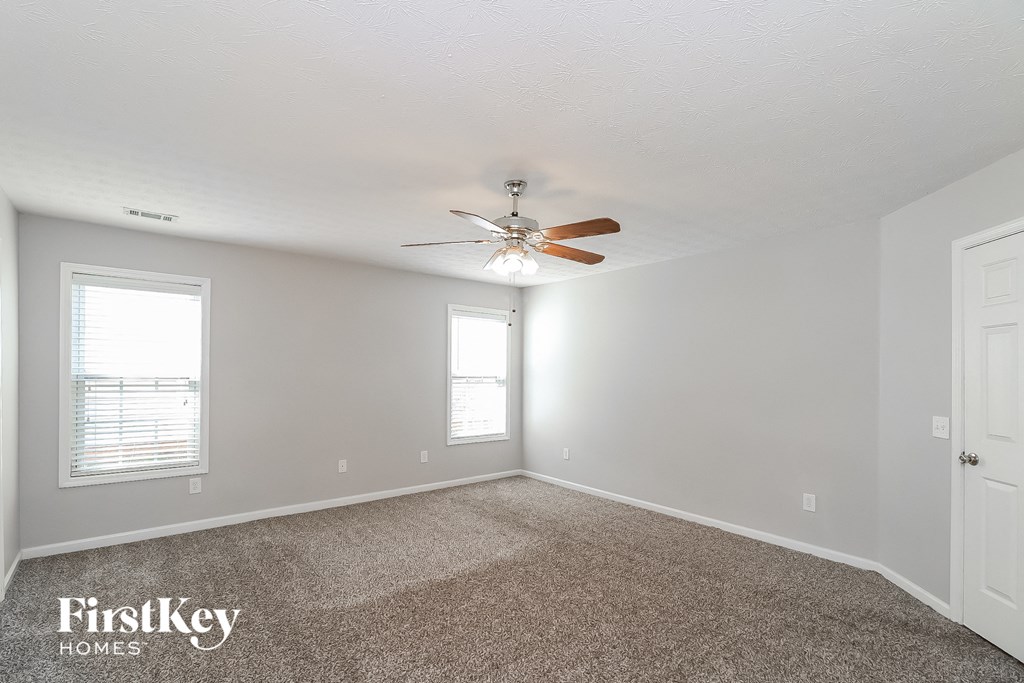 a bedroom with a ceiling fan and a carpet