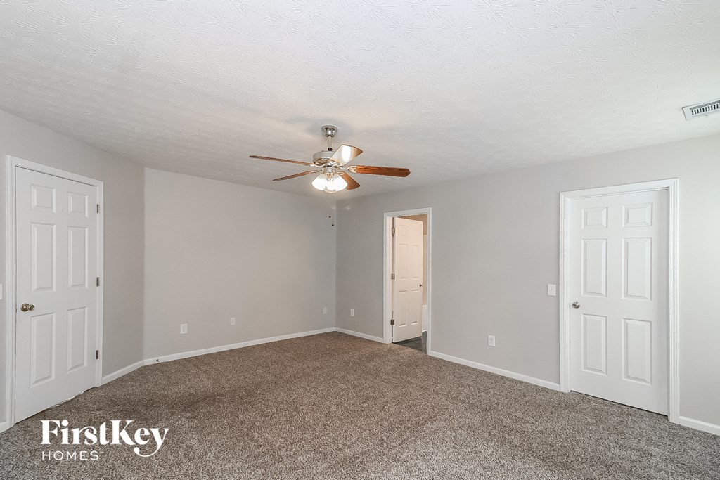 a bedroom with a ceiling fan and white doors