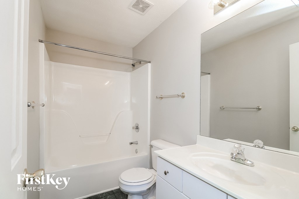 a white bathroom with a white sink and a toilet and a shower