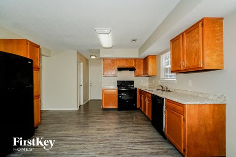 A kitchen with wooden cabinets and a black fridge.