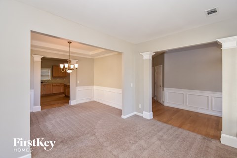 a living room and dining room with white walls and wood floors
