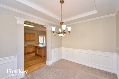 an empty dining room with white wainscoting and a chandelier