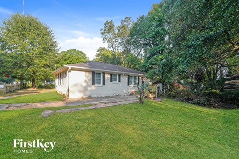 A house with a lawn and trees in the background.