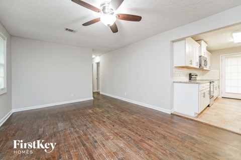 A room with a ceiling fan and wooden flooring.