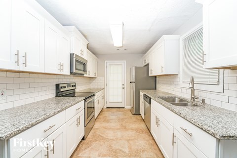A kitchen with white cabinets and a granite countertop.