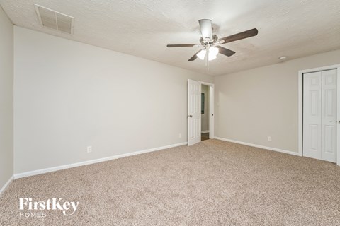 A spacious room with a carpeted floor and a ceiling fan.
