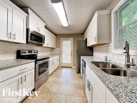 A kitchen with white cabinets and granite countertops.