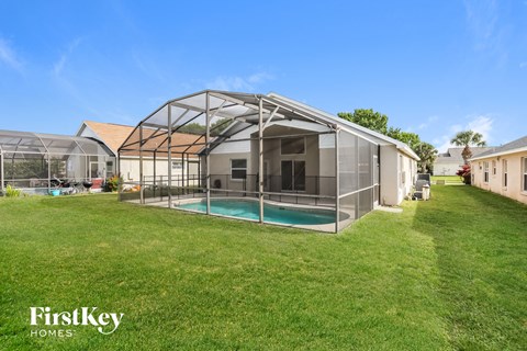 A house with a pool and a sunroom attached to it.