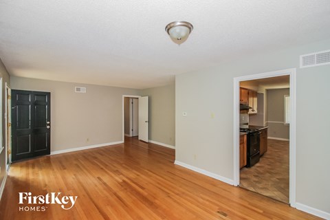A spacious room with wooden floors and a sliding door leading to another room.