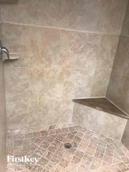 A shower area with a tiled floor and walls.
