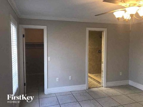 A room with a ceiling fan and two doors, one of which is open.