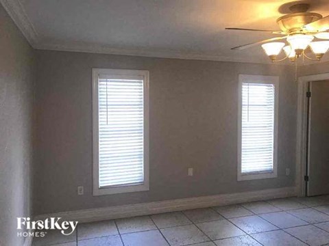 A room with two windows and a ceiling fan.