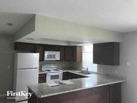A kitchen with a white refrigerator and a granite counter top.