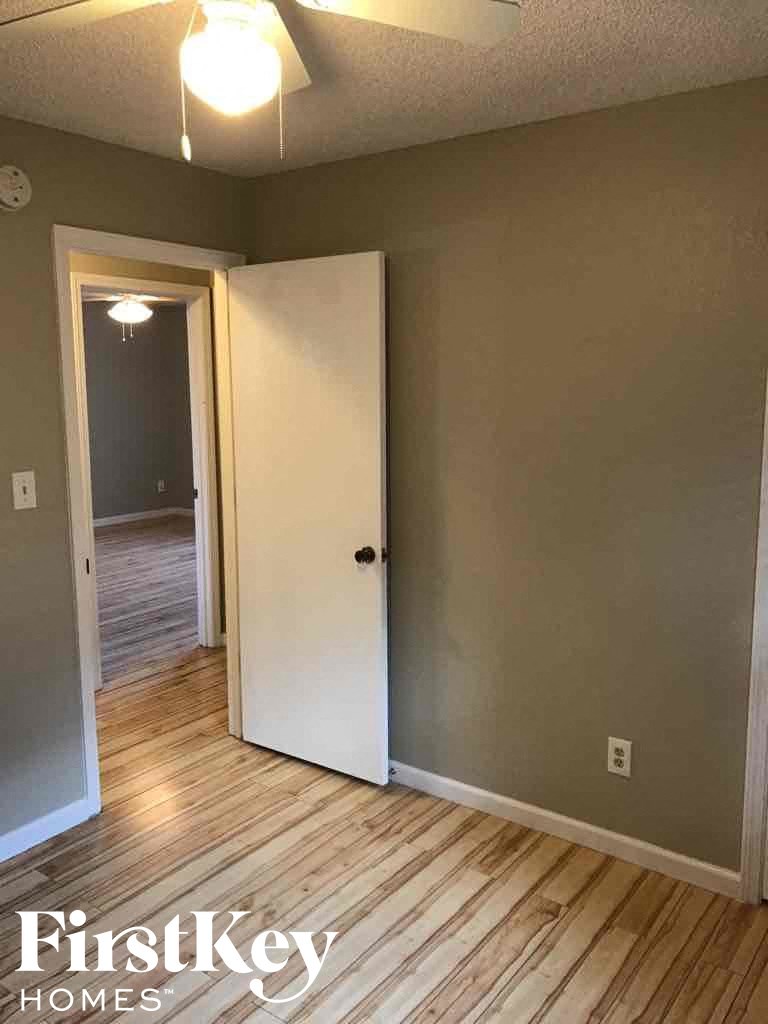 an empty room with a door open to a hallway and a door into a bedroom