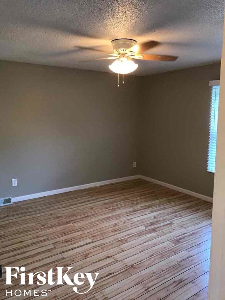 a empty room with wood floors and a ceiling fan
