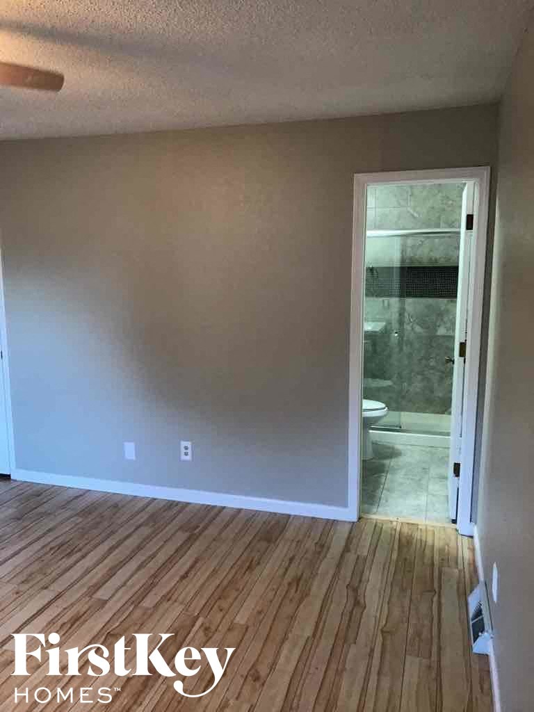 an empty room with wooden floors and a door to a bathroom