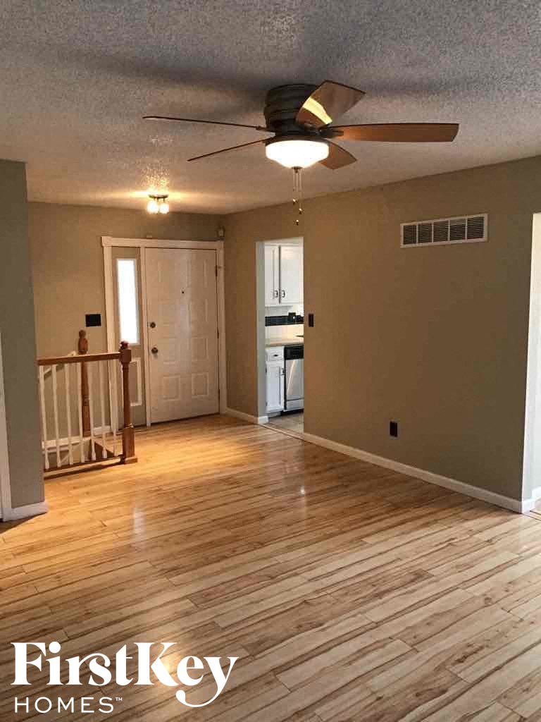 an empty living room with a ceiling fan and wood floors