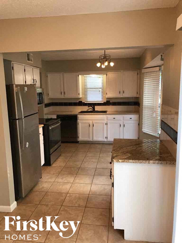 a kitchen with white cabinets and a stainless steel refrigerator