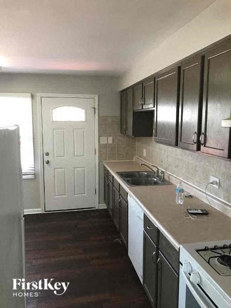 A kitchen with a white door and a stove top oven.
