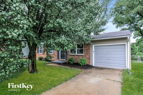 a small brick house with a driveway and a white garage door