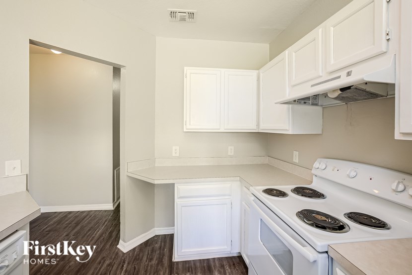 A kitchen with a stove top oven and a white cabinet.