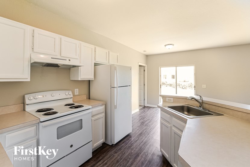A kitchen with white appliances and wooden floors.