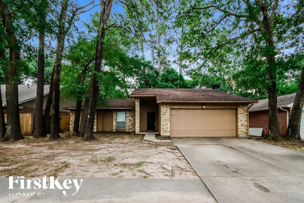 A house with a garage is surrounded by trees.