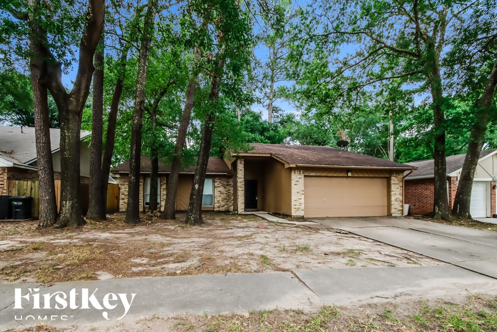 A house with a brown garage door is surrounded by trees.