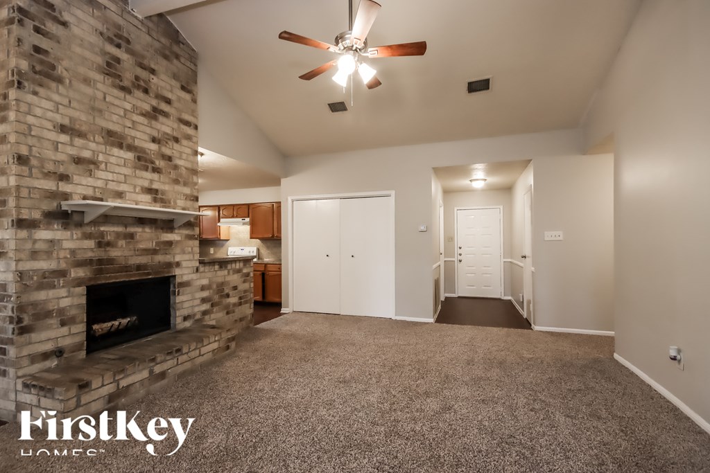 A spacious room with a stone fireplace and a ceiling fan.