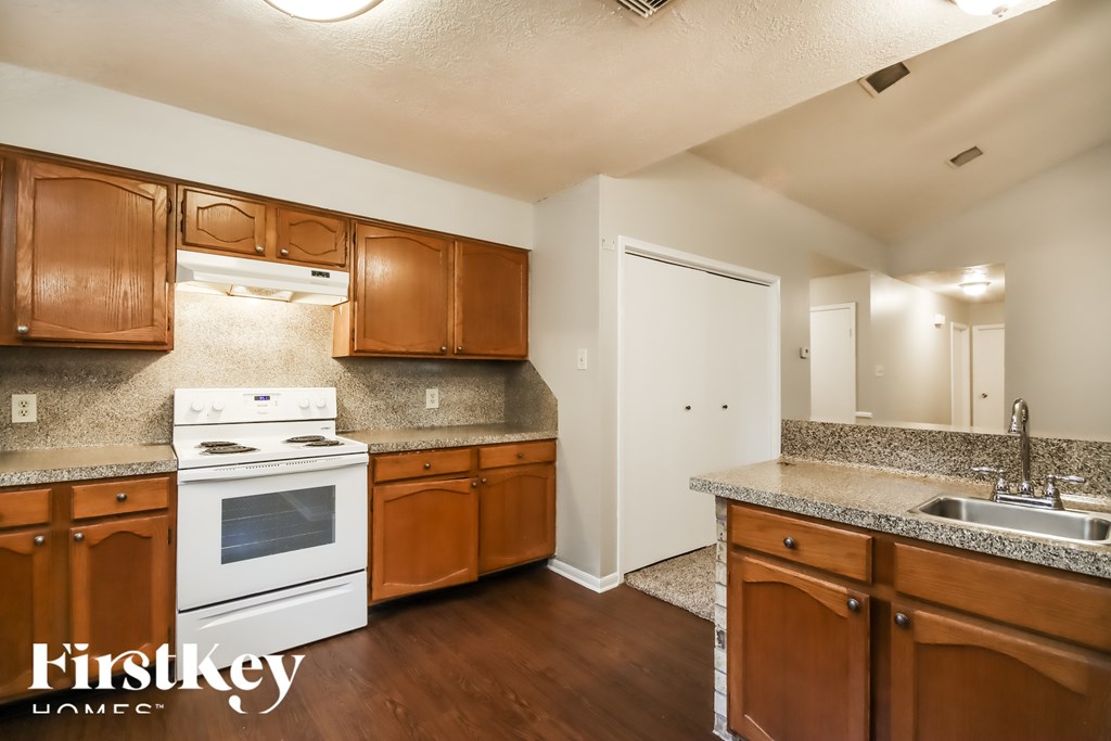 A kitchen with wooden cabinets and a white stove top oven.