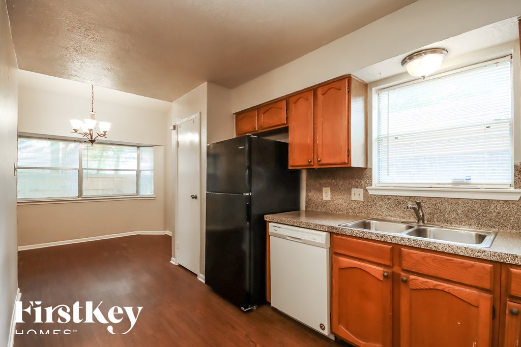 A kitchen with wooden cabinets and a black refrigerator.
