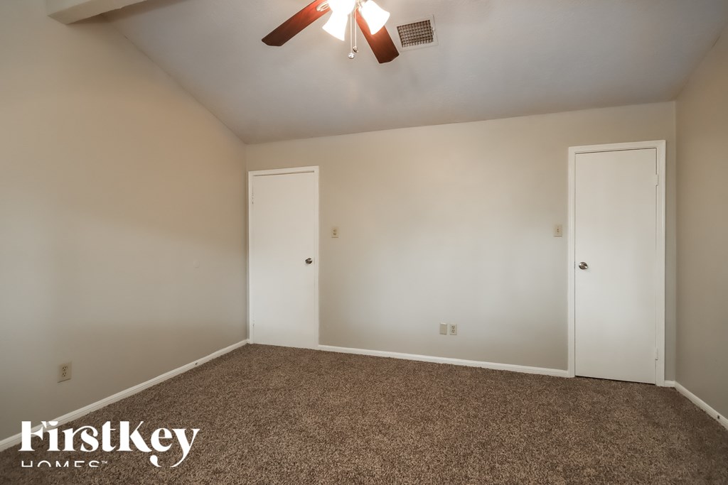 A room with a carpet floor and two white doors.