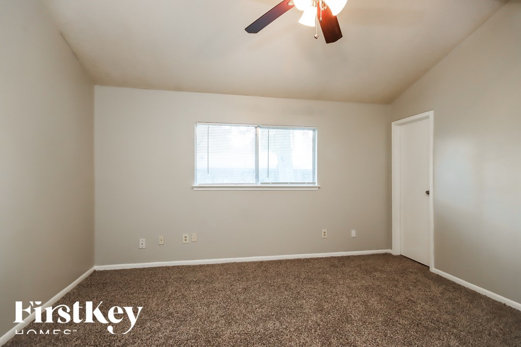 A room with a carpet floor, a ceiling fan, and a window with blinds.