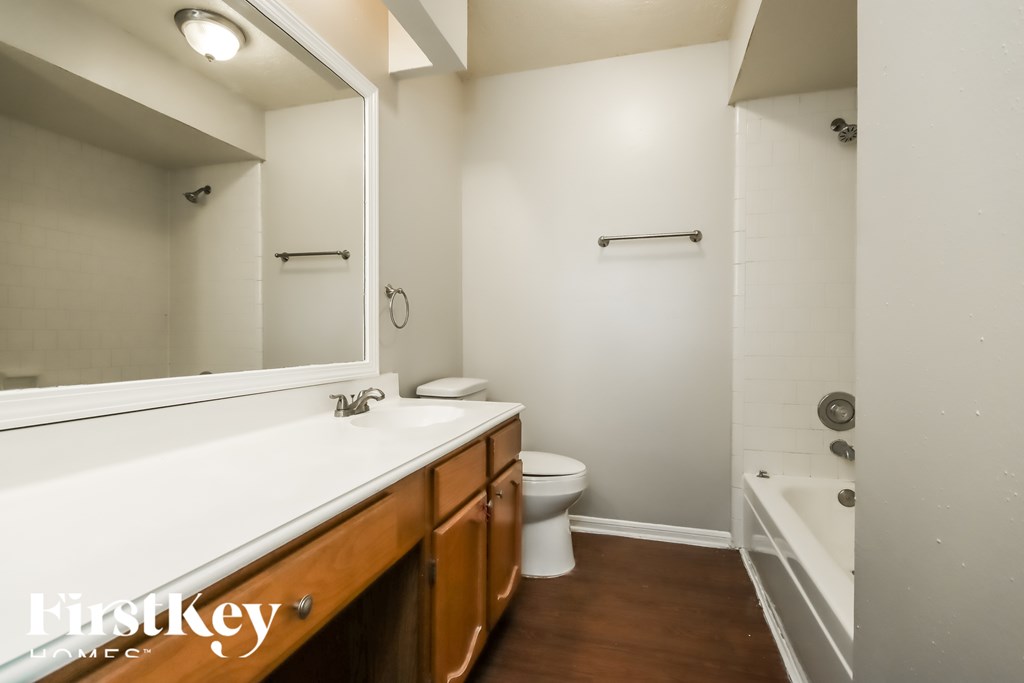 A bathroom with a white counter top and wooden cabinets.