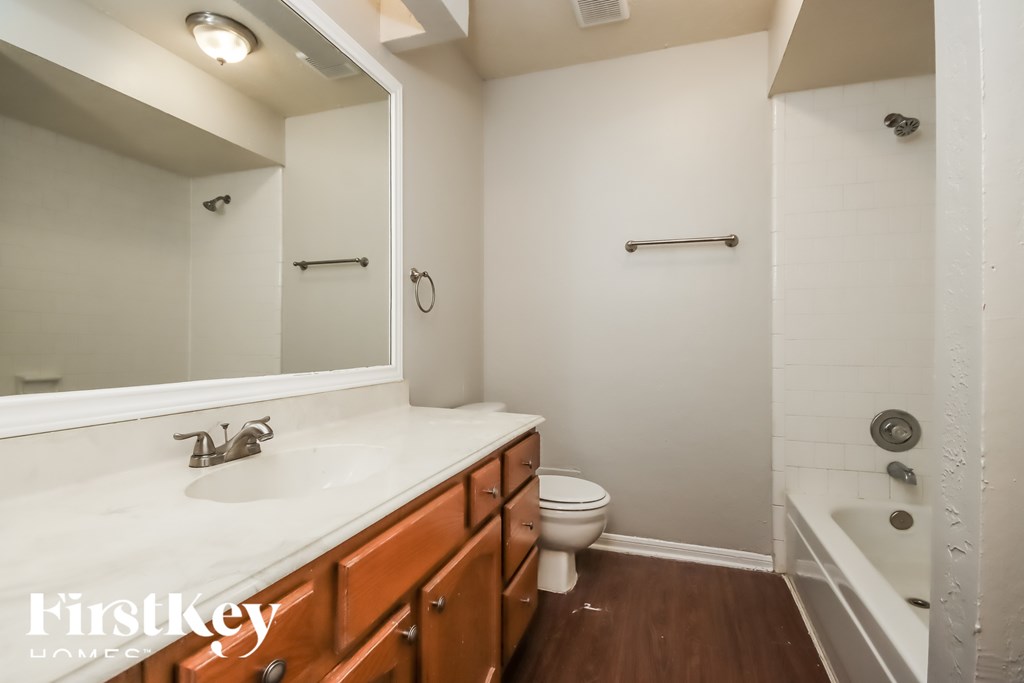 A bathroom with a white sink and brown drawers.