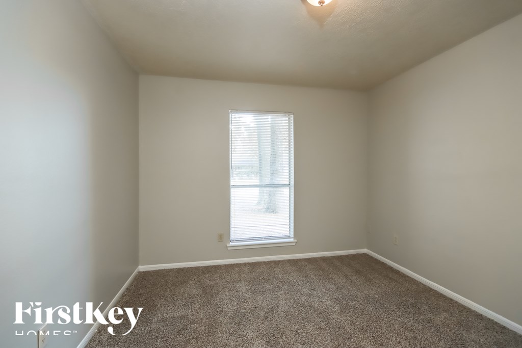 A room with a carpeted floor and a window letting in light.