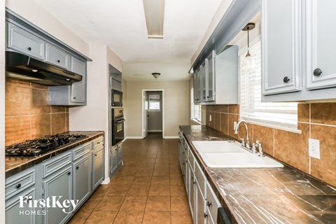 A kitchen with a stove top oven and a sink.