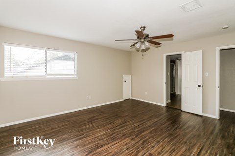 A spacious room with a ceiling fan and wooden flooring.