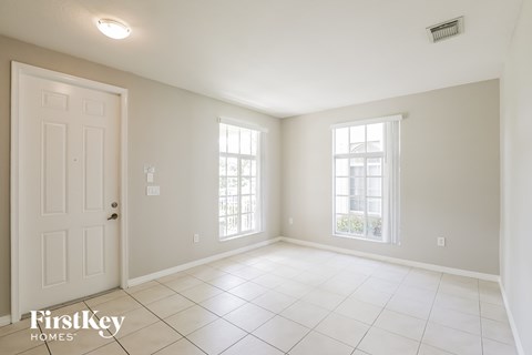 an empty living room with a white door and tiled floor
