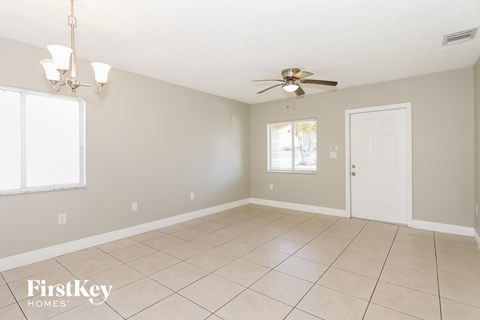 an empty living room with a ceiling fan and tiled floor