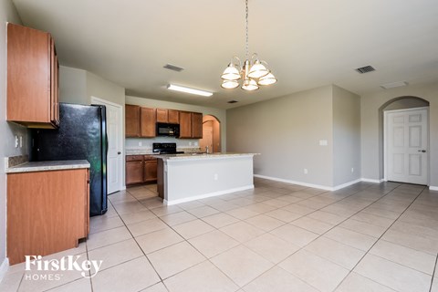A kitchen with wooden cabinets and a black refrigerator.