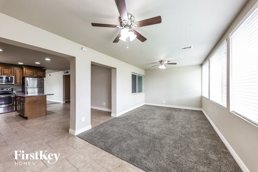 A spacious living room with a kitchen in the background and a rug on the floor.