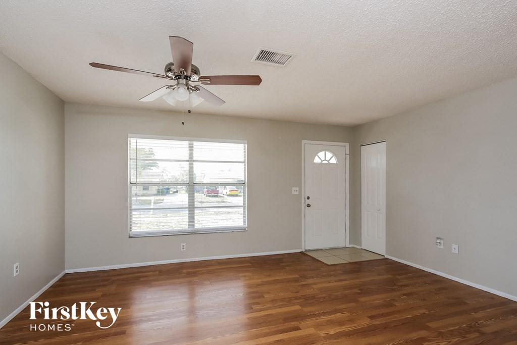 A room with a ceiling fan and wooden floors.